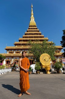 Buddhist monk stands in front of nine-story stupa Phra Mahathat Kaen Kakhon