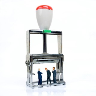Three figurines representing business men under an ink pad