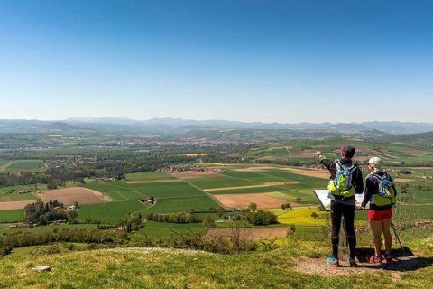 Hikers enjoying the view from Usson village on plain of Limagne and the volcanic landscape of the Chaine des Puys