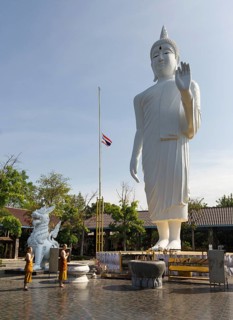 Monks in front of a gigantic Buddha statue in Wat Pa Thamma Utthayan