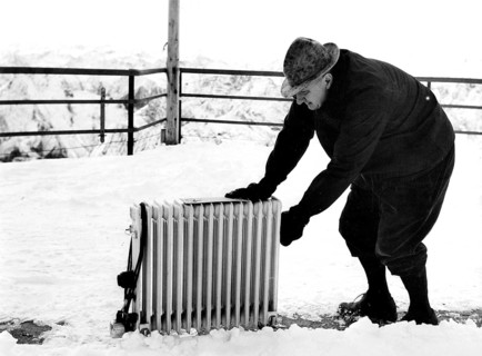 Old man pushes radiator through snow
