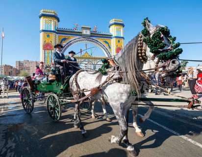 Decorated horse-drawn carriage in front of illuminated entrance gate