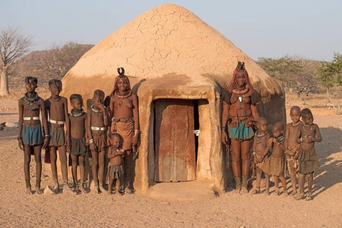 Himba women and children in front of a mud hut