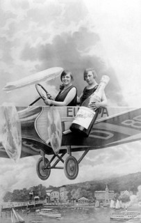 Two women with a bottle of sparkling wine in an aircraft mock-up