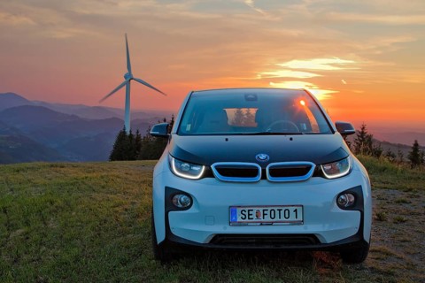 BMW electric car type i3 at the wind farm at sunset