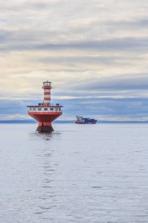 Lighthouse Phare du Haut-Fond Prince in Saint Lawrence River with freighter in the back
