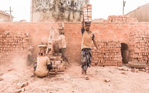 Workers with bricks on their heads in the brickyard