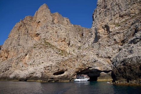 Tourist boat entering the sea cave Grotta Perciata