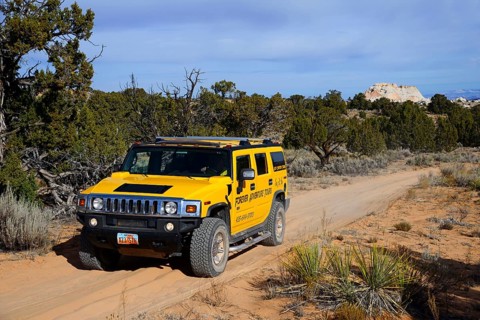 Yellow Hummer driving on a sand track to White Pocket Canyon