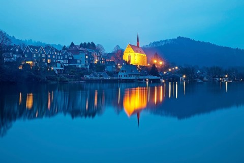 Beyenburg reservoir with the illuminated church of St. Mary Magdalene in the evening