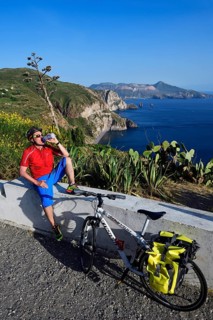 Cyclist pausing on the Belvedere Quattrocchi with a view over the rocks Faraglione on the island Vulcano