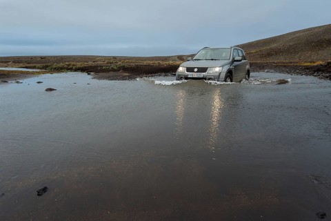Off road vehicle drives through waterfurt