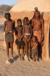 Himbafrau with children in front of a mud hut