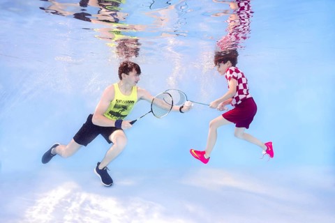 Two teenagers playing badminton underwater