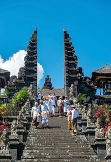 Balinese believers in traditional clothing go down stairs