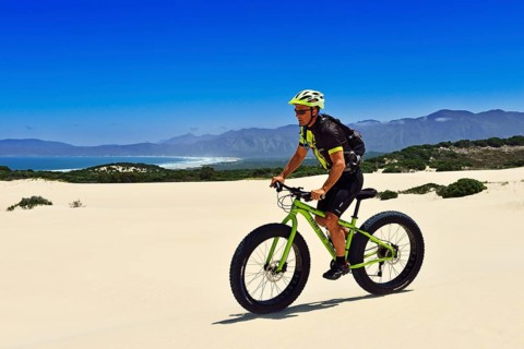 Mountain biker with fat bike in sand dunes