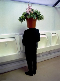 Man with flowerpot on his head in the toilet