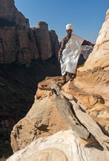 Coptic priest on a rock ledge at the entrance to Abuna Yemata monolithic church