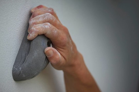 A hand holding on to an artificial climbing grip
