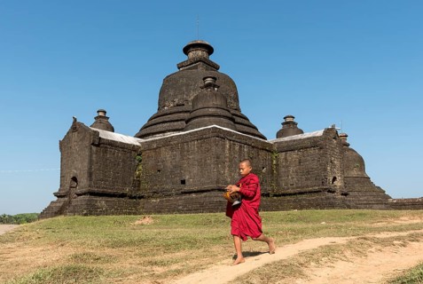 Novice Buddhist monk collects morning alms in front of Laymyetnha Paya