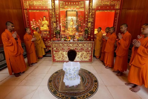 Buddhist Sacrifice Ceremony with praying monks and kneeling woman