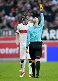 Referee Bibiana Steinhaus shows Christian Gentner of VfB Stuttgart with face mask the yellow card
