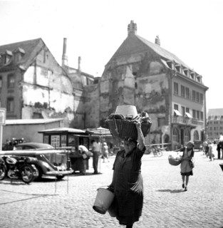 A woman carries a wooden basket on her head