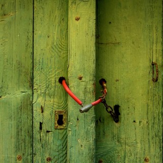 Red bicycle lock closing a green wooden door