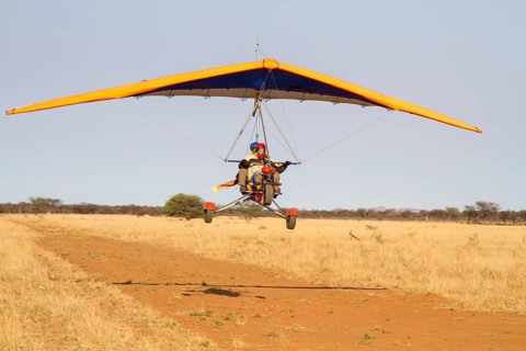 Ultra-light plane flying over sandy runway