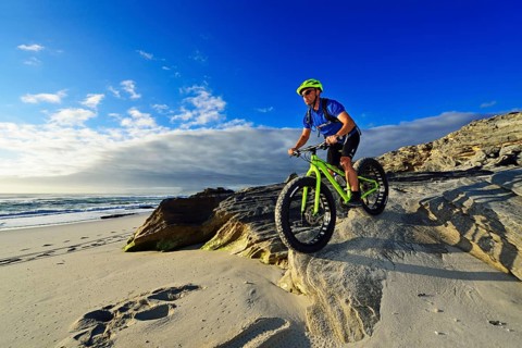 Mountain biker with fat bike on the beach