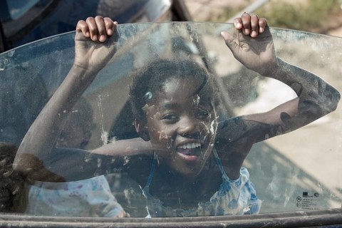 A girl is playing a car wreck in the slum district