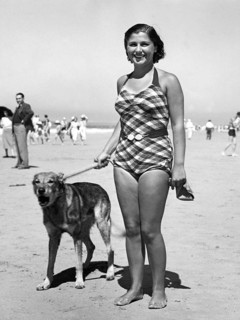 Woman in bathing suit with dog on the beach
