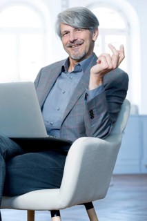 Man sits with laptop in his office chair