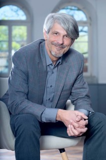Man sits smiling in an armchair