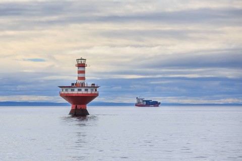 Lighthouse Phare du Haut-Fond Prince in Saint Lawrence River with freighter in the back