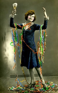 Woman celebrates New Year's Eve with champagne and paper snakes