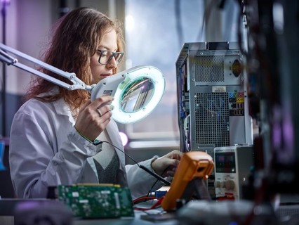 Technician with white lab coat with a measuring device in an electronics laboratory