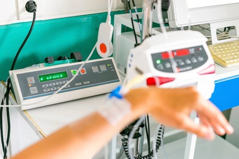 Hand with peripheral venous catheter and equipment to dose epidural during delivery