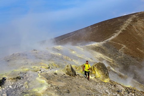 Trailrunner surrounded by sulfur fumaroles and chloride crusts on the crater rim