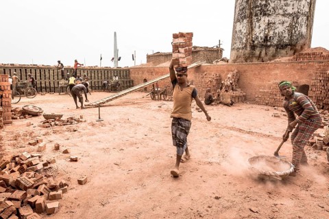 Workers with bricks on their heads in the brickyard