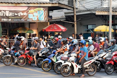 Many moped drivers are waiting at an intersection