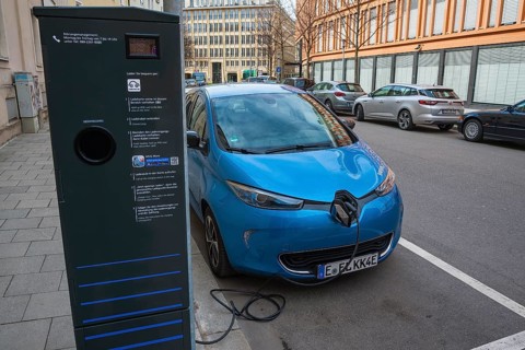 Electric car is charged at green electricity charging station with charging cable