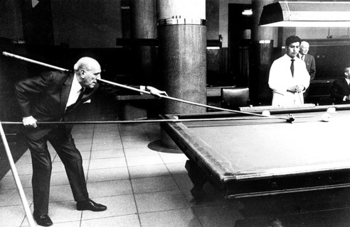 Man playing with long cue billiard