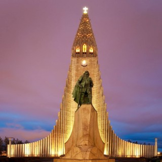Illuminated Hallgrimskirkja with statue of Leif Eriksson at dusk