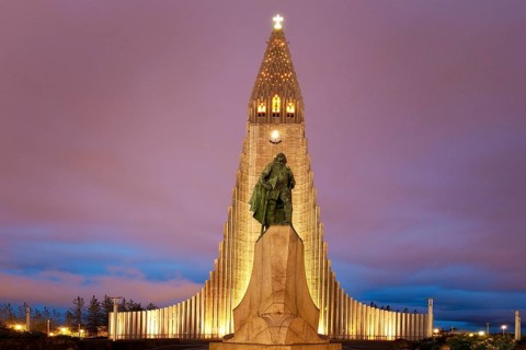 Illuminated Hallgrimskirkja with statue of Leif Eriksson at dusk