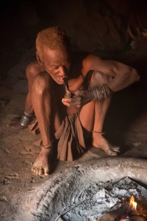 Old Himba chief sitting at the fire in his hut