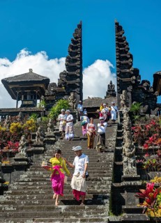 Balinese believers in traditional clothing go down stairs