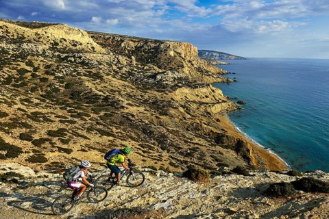 Two mountain bikers cycle along the rocky coast