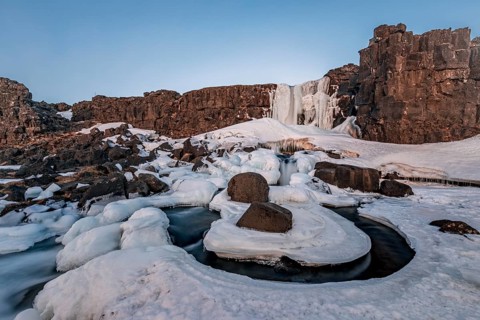Partially frozen waterfall Oxararfoss in winter