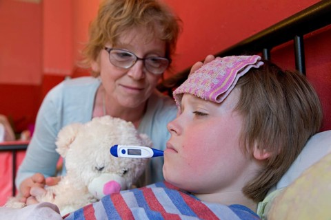 Mother comforts sick son in bed